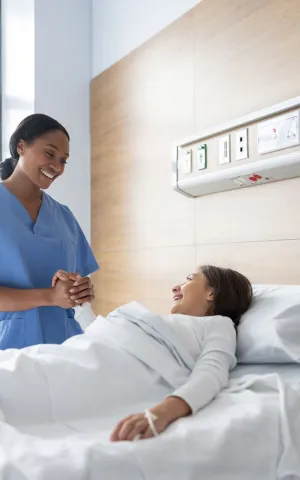 Infirmière tenant la main d'une patiente alitée.